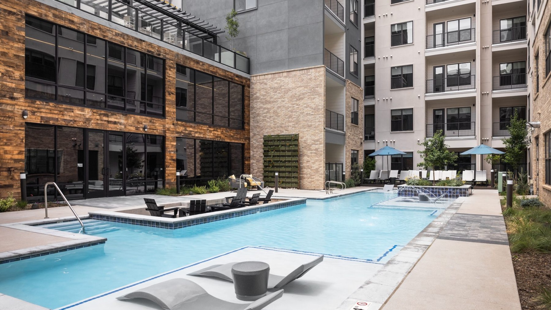 swimming pool in a courtyard with lounge chairs and umbrellas