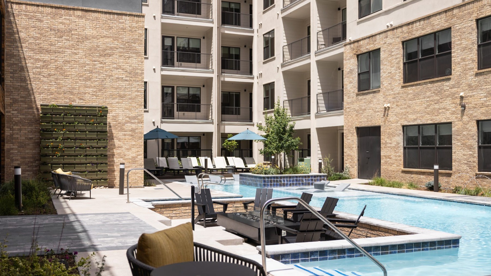 swimming pool in a courtyard with lounge chairs and umbrellas