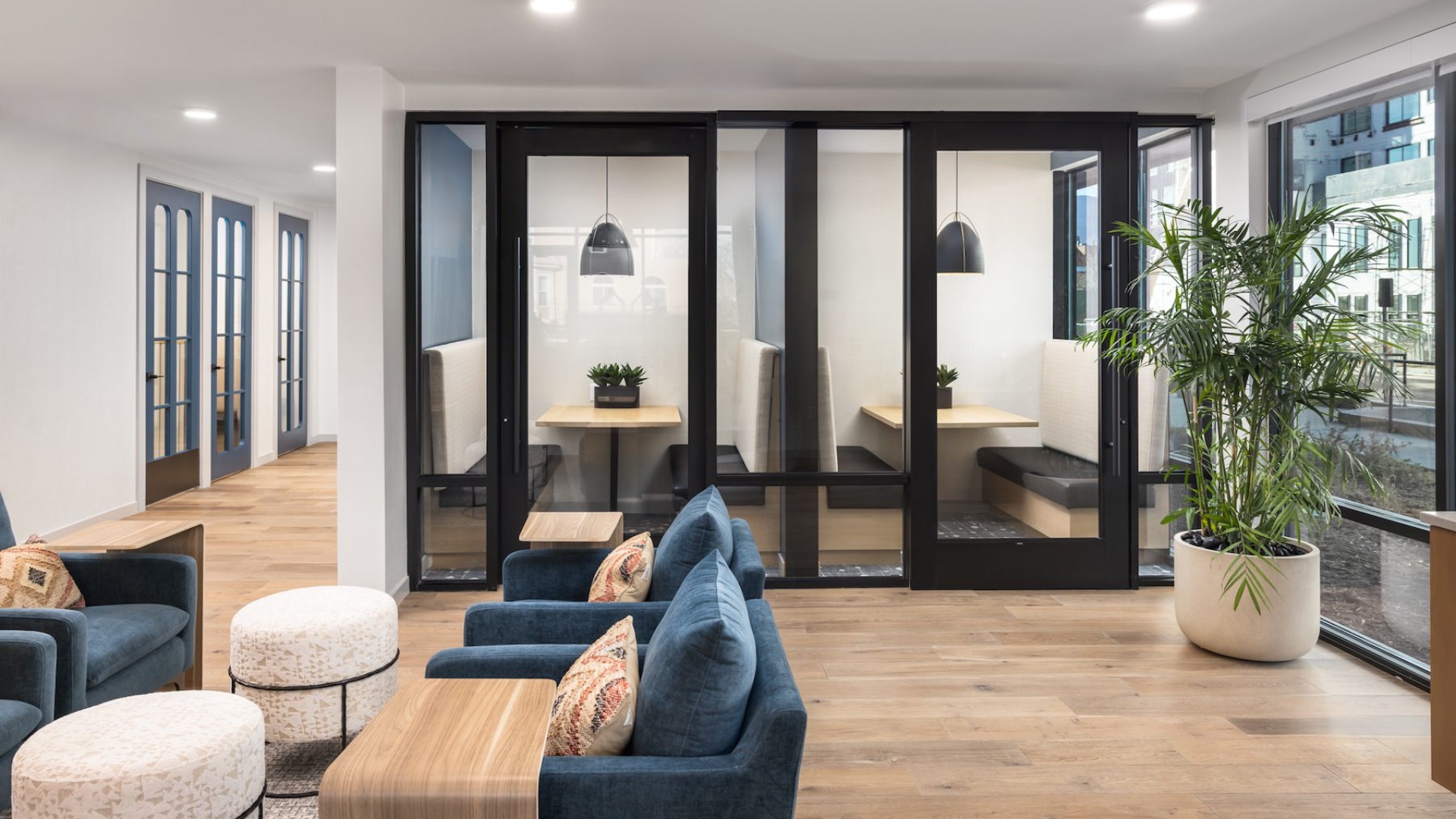 seating area with a plant in the corner and private rooms with glass doors