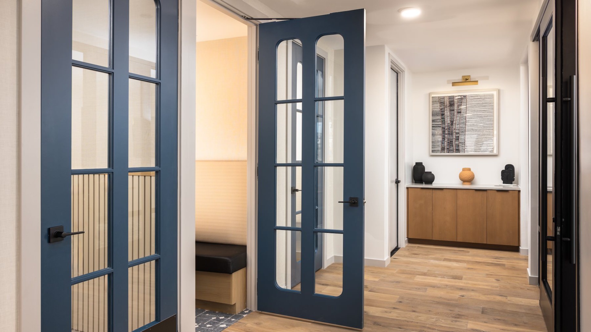 a hallway with doors to private rooms and wood-style flooring