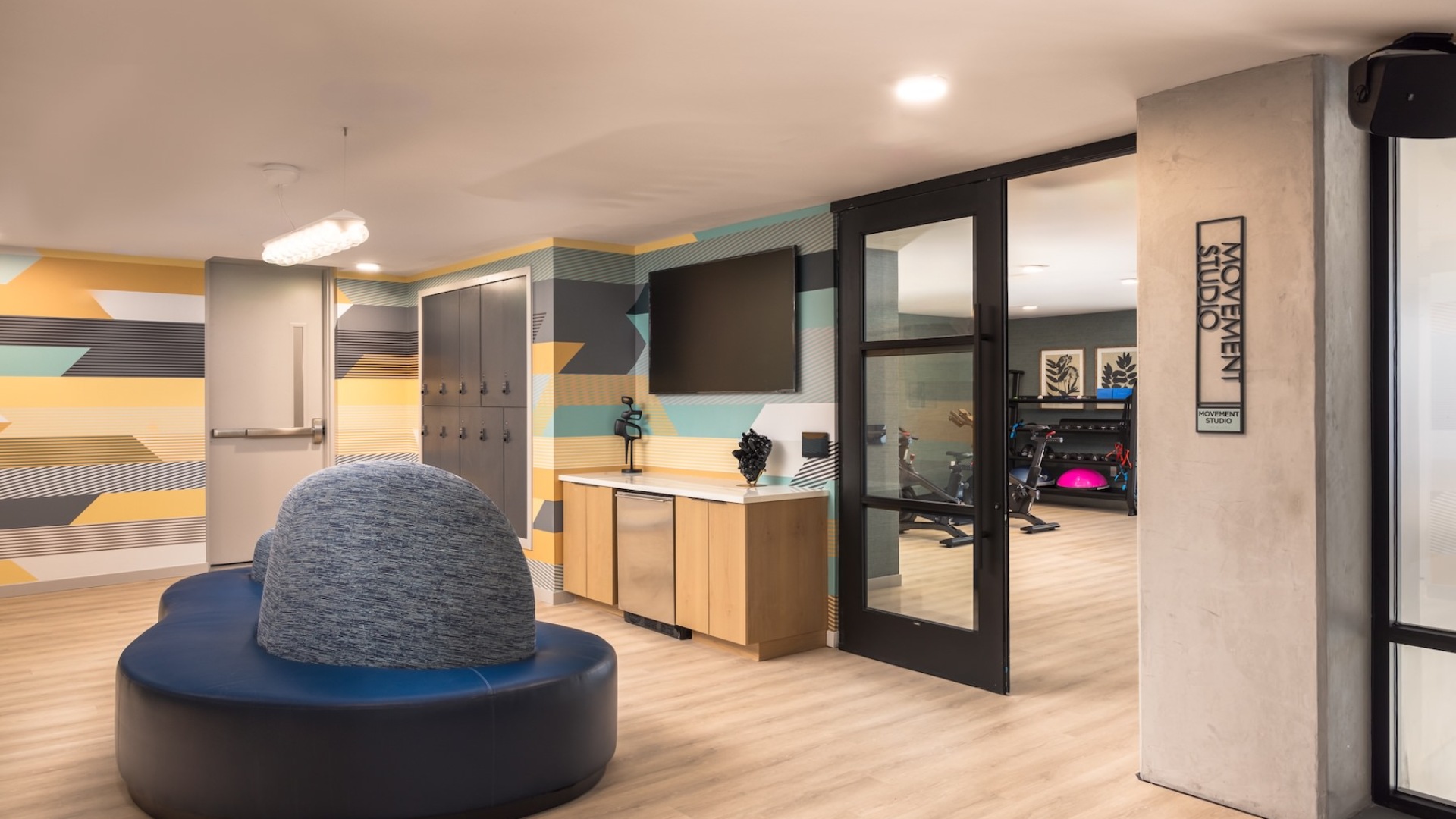 a room with a large couch, tv and lockers