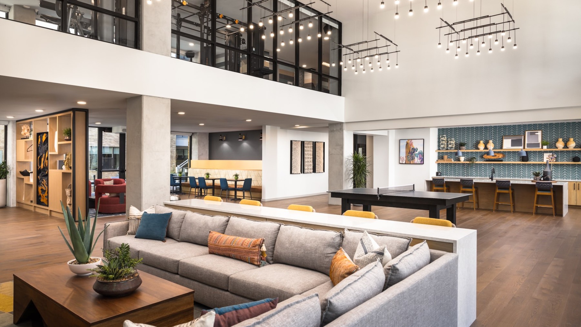 a large room with a ping pong table, seating area, and community kitchen