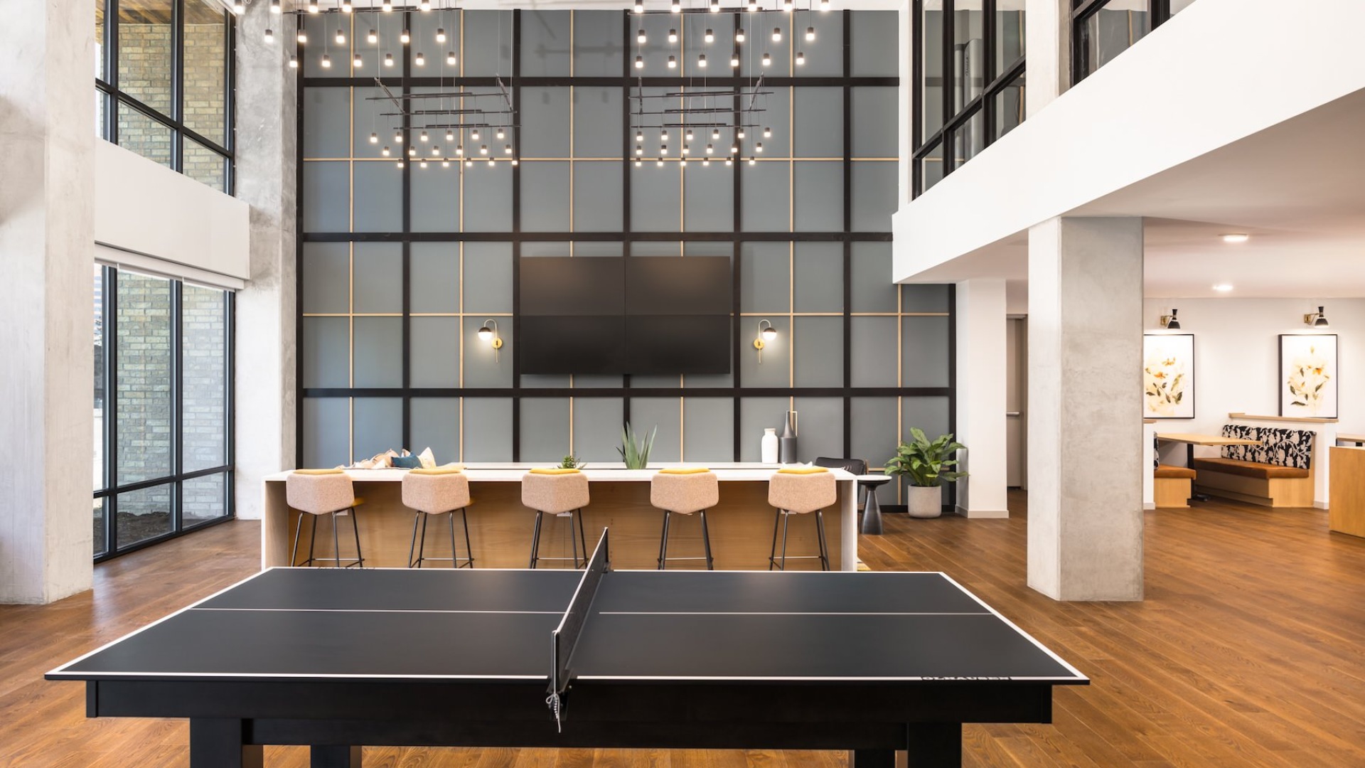 a room with a ping pong table and a large seating area with a flat screen tv