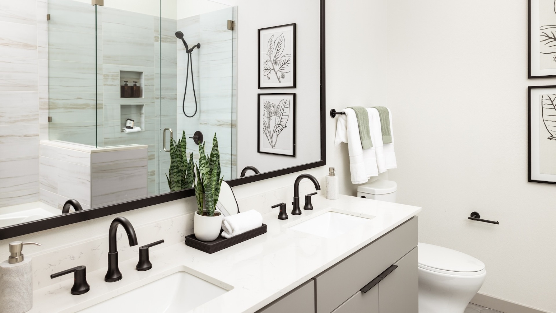 bathroom with a large mirror, glass shower and two sinks