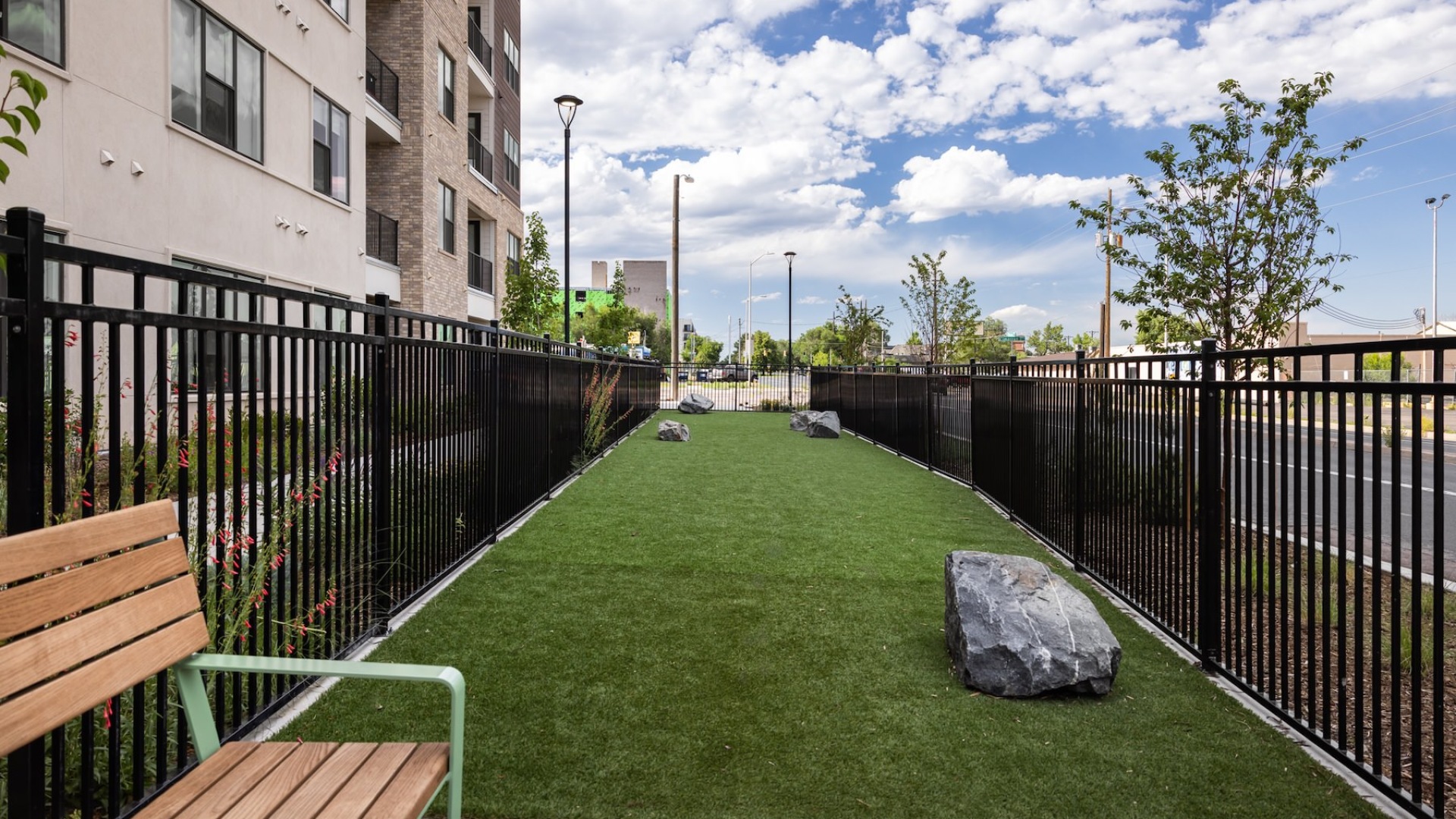 fenced-in area with grass, large rocks and a bench
